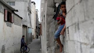 Un joven palestino en bicicleta observa a un niño sentado en un muro en el campo de refugiados de Jabalia.