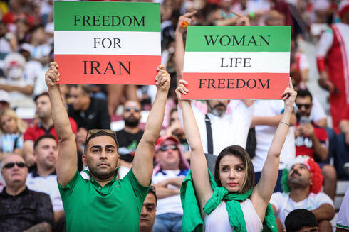 Hinchas iraníes sostienen carteles contra el gobierno.