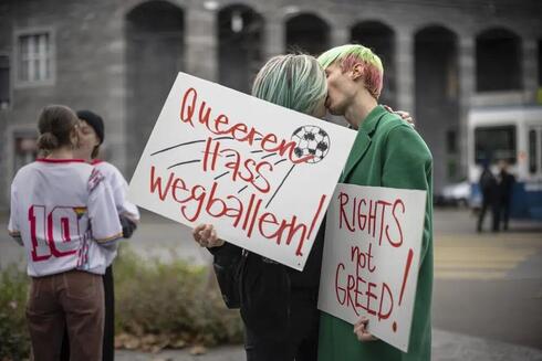 Manifestantes se besan mientras sostienen pancartas que dicen "Dispara odio queer" y "Derechos no codicia" durante una manifestación sobe los derechos humanos de las personas LGBTQ en Catar y la responsabilidad de la FIFA. 