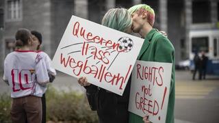 Manifestantes se besan mientras sostienen pancartas que dicen "Dispara odio queer" y "Derechos no codicia" durante una manifestación sobe los derechos humanos de las personas LGBTQ en Catar y la responsabilidad de la FIFA. 