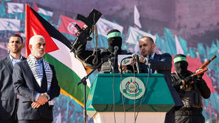 Miembro de Hamás presenta el rifle israelí junto a Yahya Sinwar (izq.), líder de Hamás en Gaza. 