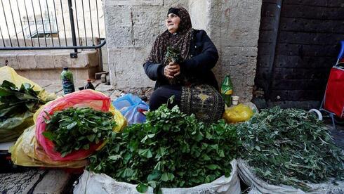 Una mujer vende hojas de plantas que se utilizan en la cocina tradicional palestina fuera de la Puerta de Damasco en la Ciudad Vieja de Jerusalem. 