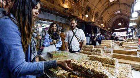 Turistas visitan un puesto de postres dulces en un mercado, la Ciudad Vieja de Jerusalem. 