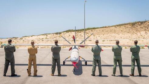 Pilotos de drones de cinco países e Israel posan delante de un Hermes-450. 