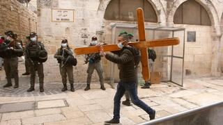Un cristiano lleva una cruz a lo largo de la Vía Dolorosa antes de la procesión del Viernes Santo en la Ciudad Vieja de Jerusalem.