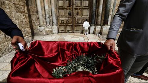 Clérigos cristianos reparten ramas de olivo a los residentes de la Ciudad Vieja de Jerusalem.