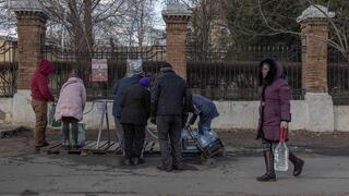 Ucranianos hacen cola para llenar botellas de agua potable. 