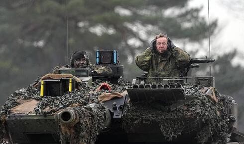 El ministro de Defensa alemán sobre un tanque del modelo enviado a Ucrania. 