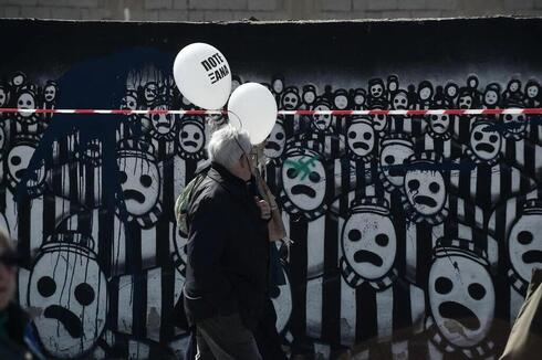Los participantes sostienen globos con la leyenda "Nunca más" mientras caminan hacia la antigua estación de ferrocarril de Salónica. 