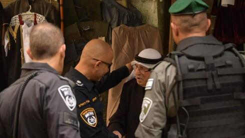 Un agente israelí saluda a un comerciante palestino en la Ciudad Vieja de Jerusalem. 