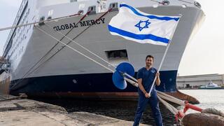 Achi Kushnir con la bandera israelí frente al "Misericordia". 