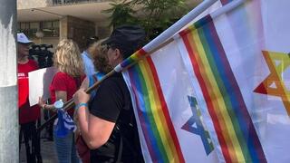 Un manifestante sostiene una bandera israelí y una bandera arco iris durante una manifestación ante el rabinato de Tel Aviv.