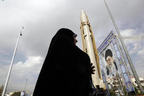Una mujer iraní camina junto al misil tierra-tierra Sejil expuesto en una exposición callejera con motivo de la "Semana de la Defensa" en Teherán. 