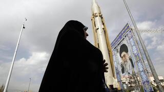 Una mujer iraní camina junto al misil tierra-tierra Sejil expuesto en una exposición callejera con motivo de la "Semana de la Defensa" en Teherán.