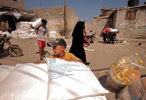 Palestinos recogen ayuda alimentaria en un centro de distribución gestionado por el Organismo de Obras Públicas y Socorro de las Naciones Unidas (OOPS), en la ciudad de Gaza. 