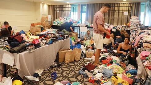 Residentes evacuados del sur de Israel clasifican la ropa donada en un hotel de Tel Aviv. 