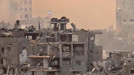Una bandera israelí vista sobre los edificios de Gaza destruidos en los ataques de las FDI.