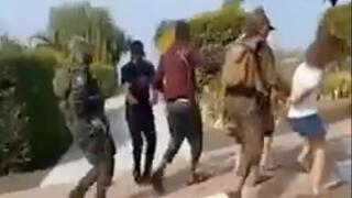 Militantes de Hamás trasladan a rehenes israelíes por una calle en Be'eri, un kibutz en el sur de Israel, según muestra un video publicado en X