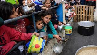 Refugiados palestinos hacen cola para conseguir comida en Rafah. 